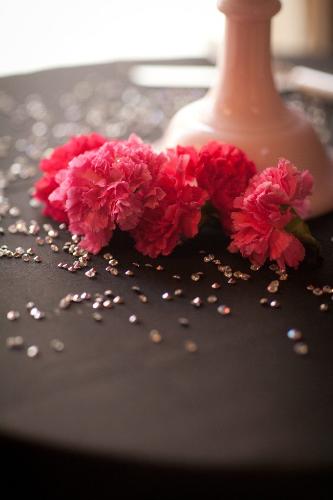 pink carnations on black tablecloth with loose rhinestones